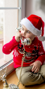 Little boy wearing a Santa hat talks on the phone with someone from NORAD Tracks Santa 
