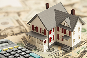 Home on a pile of cash next to a calculator, representing the savings of a VA home loan