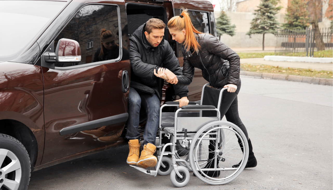 A woman helps a disabled veteran out of her car after driving him to an appointment