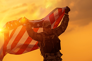 A member of the military holds the American flag over his head in celebration of his VA benefits